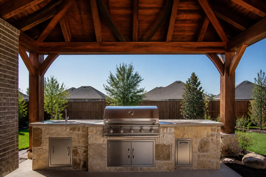 A grill set beneath the roof of a pergola or patio cover